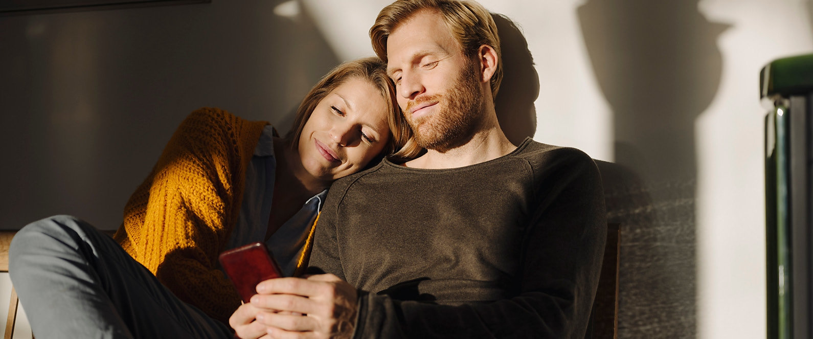 Pärchen lehnt aneinander Pärchen lehnt aneinander und schaut auf Handy.