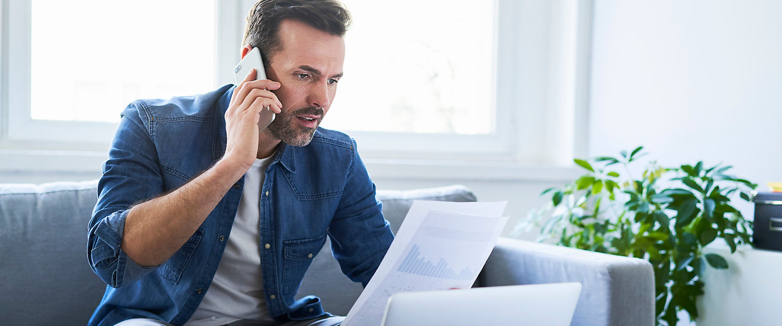 Mann telefoniert vor Laptop