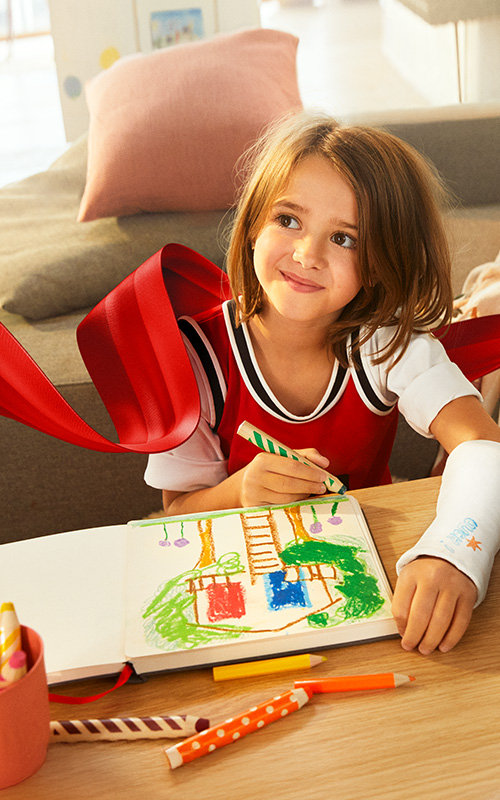 Ein Mädchen malt ihre Träume in ein Buch und lächelt.