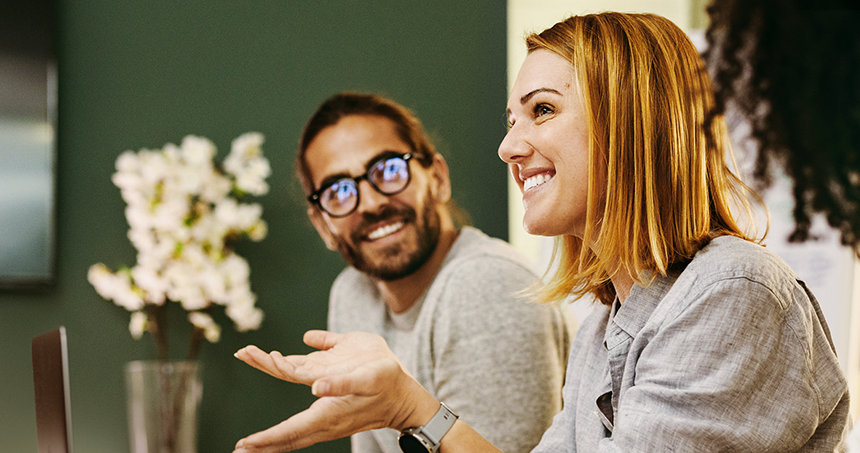 Zwei Personen sitzen lachende nebeneinander und sind in einem Gespräch
