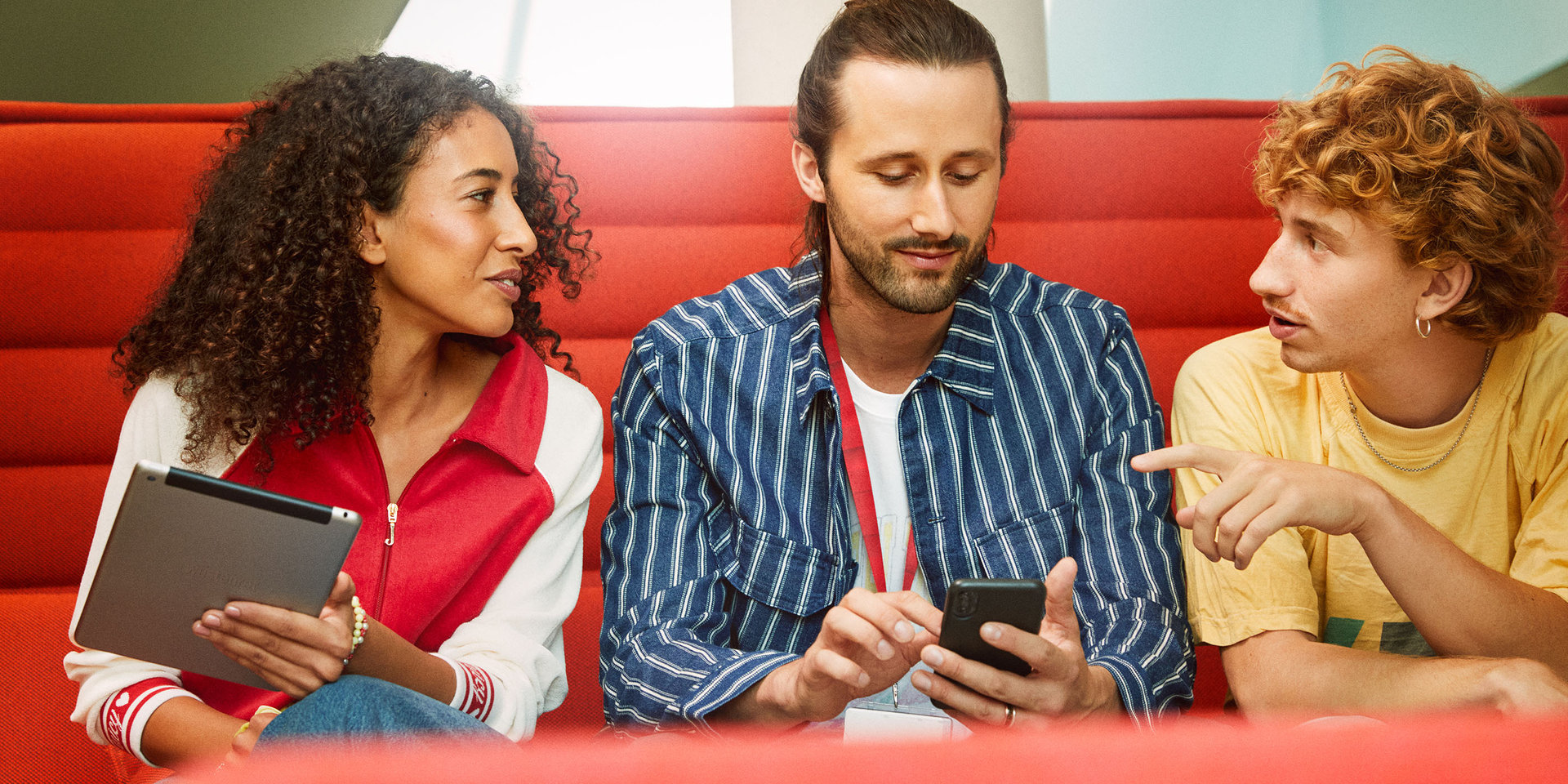 zwei Kollegen und eine Kollegin der WTEC sitzen bei einer Besprechung auf einer Couch und halten ein Tablet und ein Smartphone in der Hand