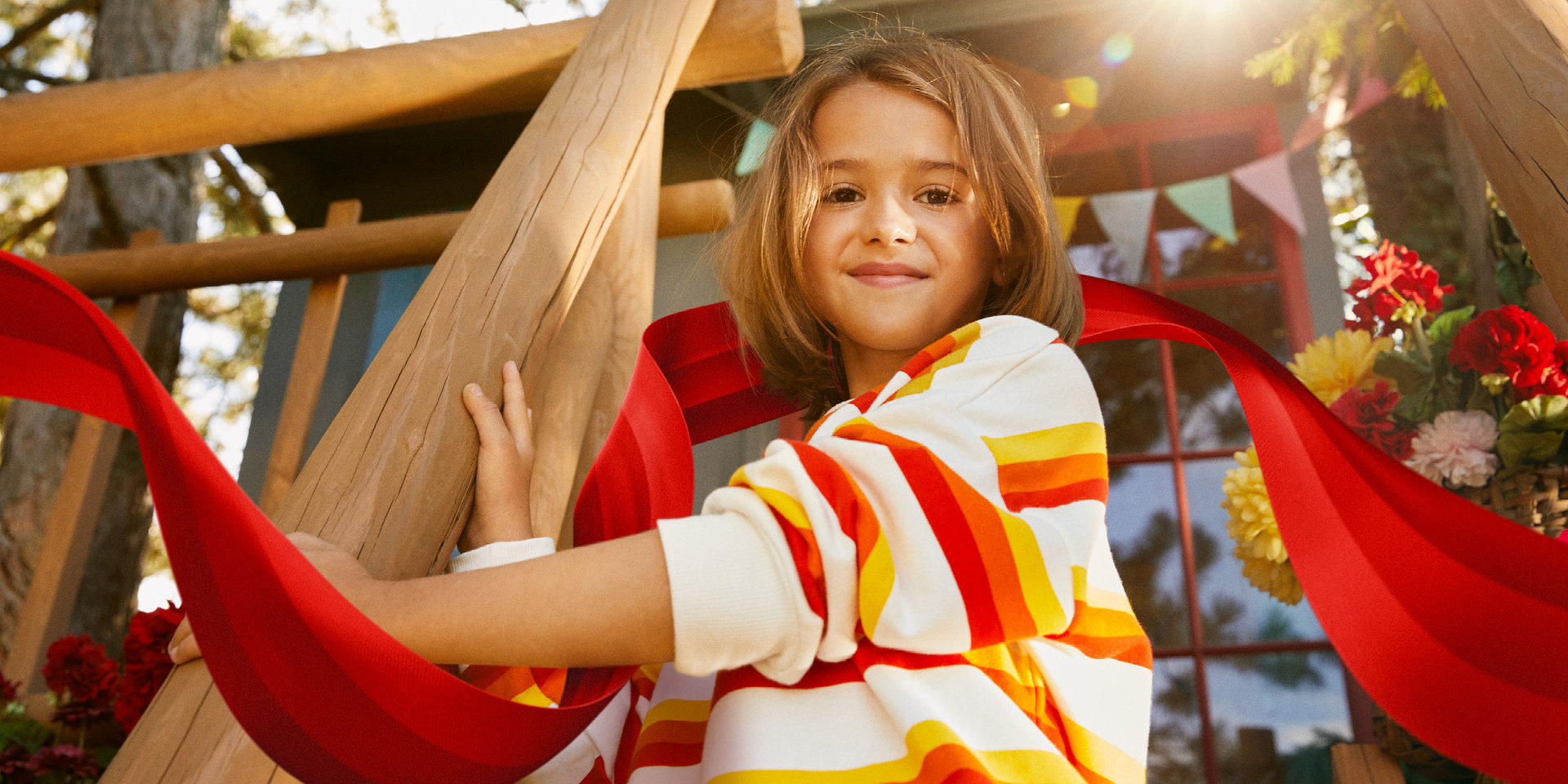 Mädchen am Baumhaus Ein Mädchen steht auf der Treppe zu einem Baumhaus und lächelt.