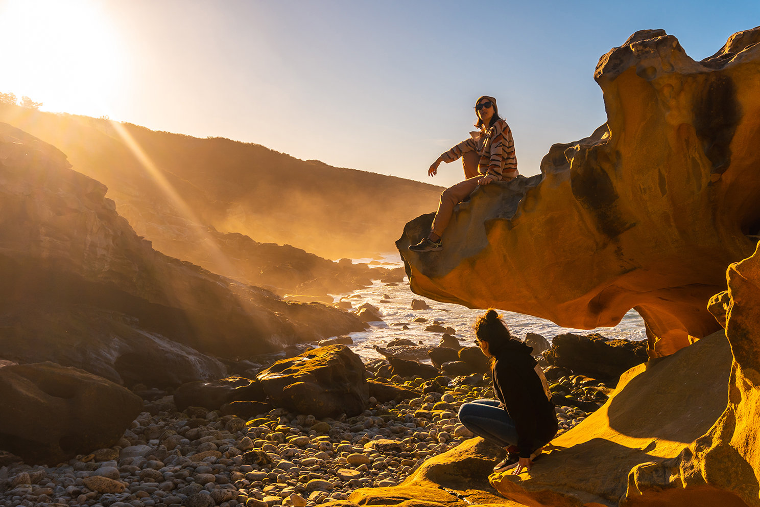 Eine Landschaft mit Felsen und zwei sitzenden Personen. 