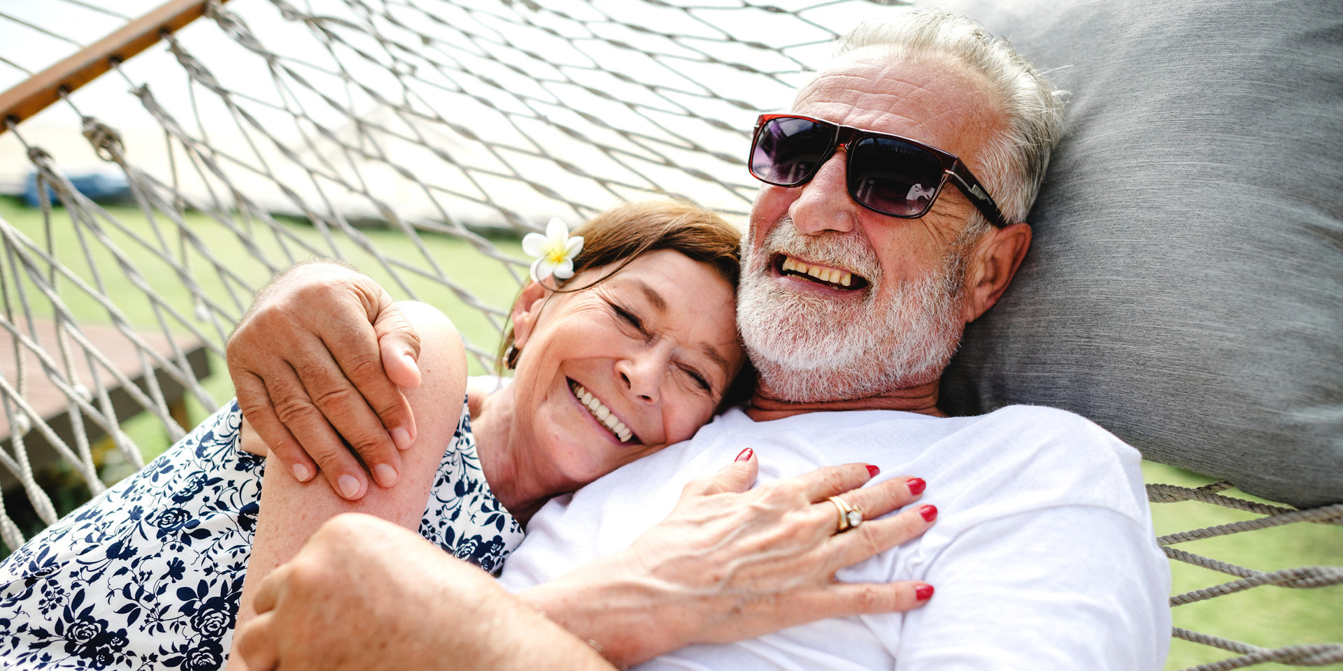 Ein Mann und eine Frau liegen gemeinsam in einer Hängematte und freuen sich, für den Ernstfall gut abgesichert zu sein.