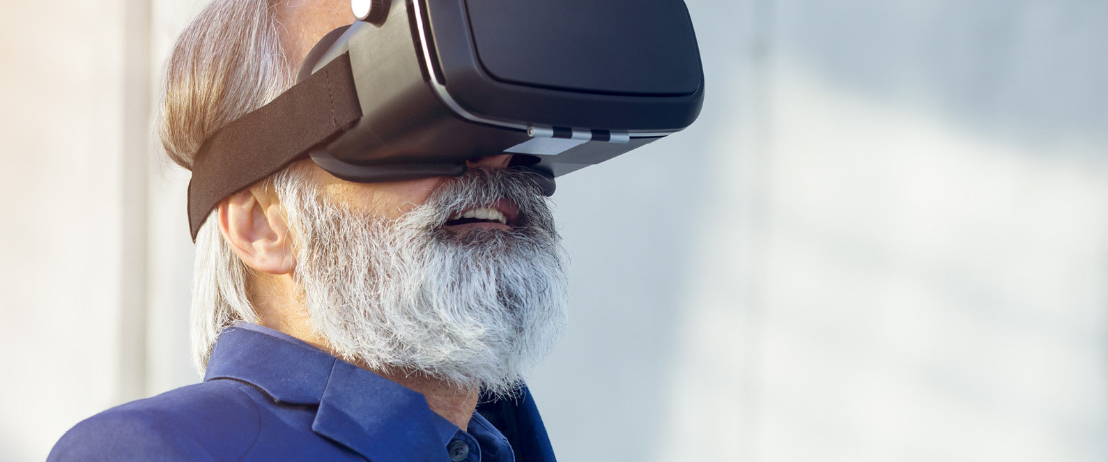 Ein älterer Mann mit weißem Bart nutzt eine VR-Brille.