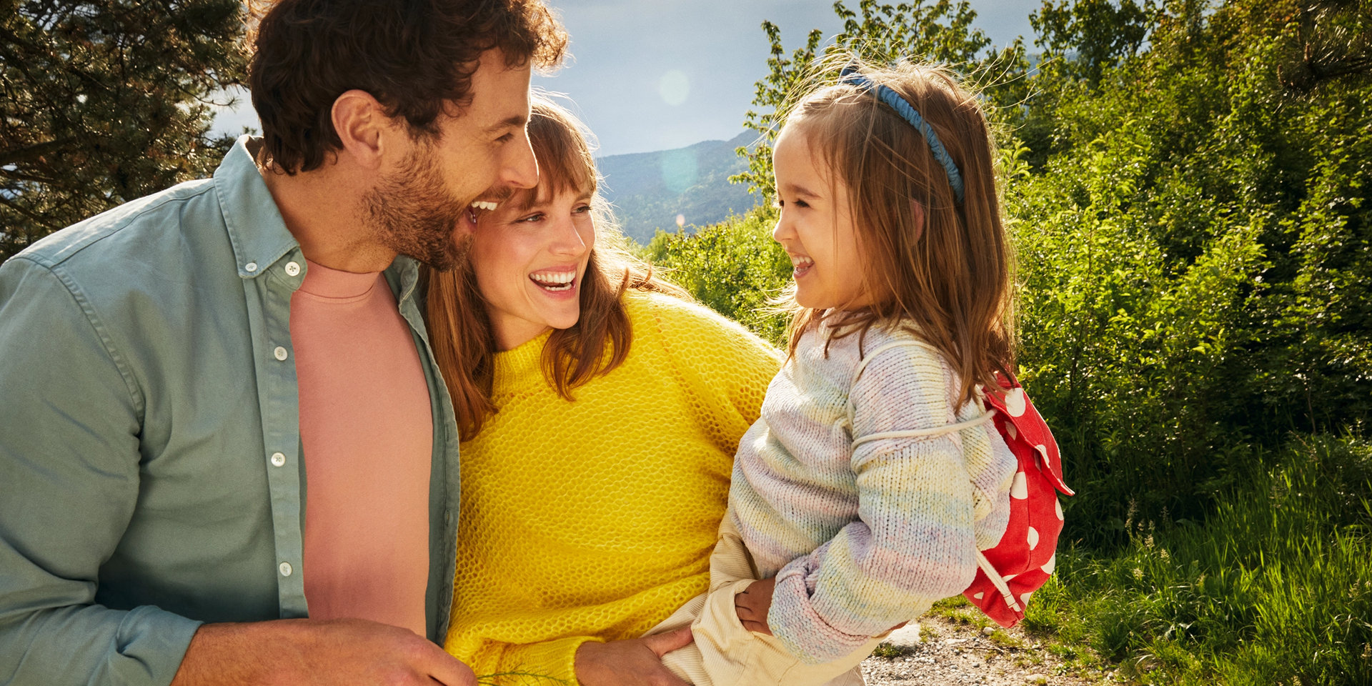 Ein Mann und eine Frau halten ihr Kind auf dem Arm und strahlen glücklich. 