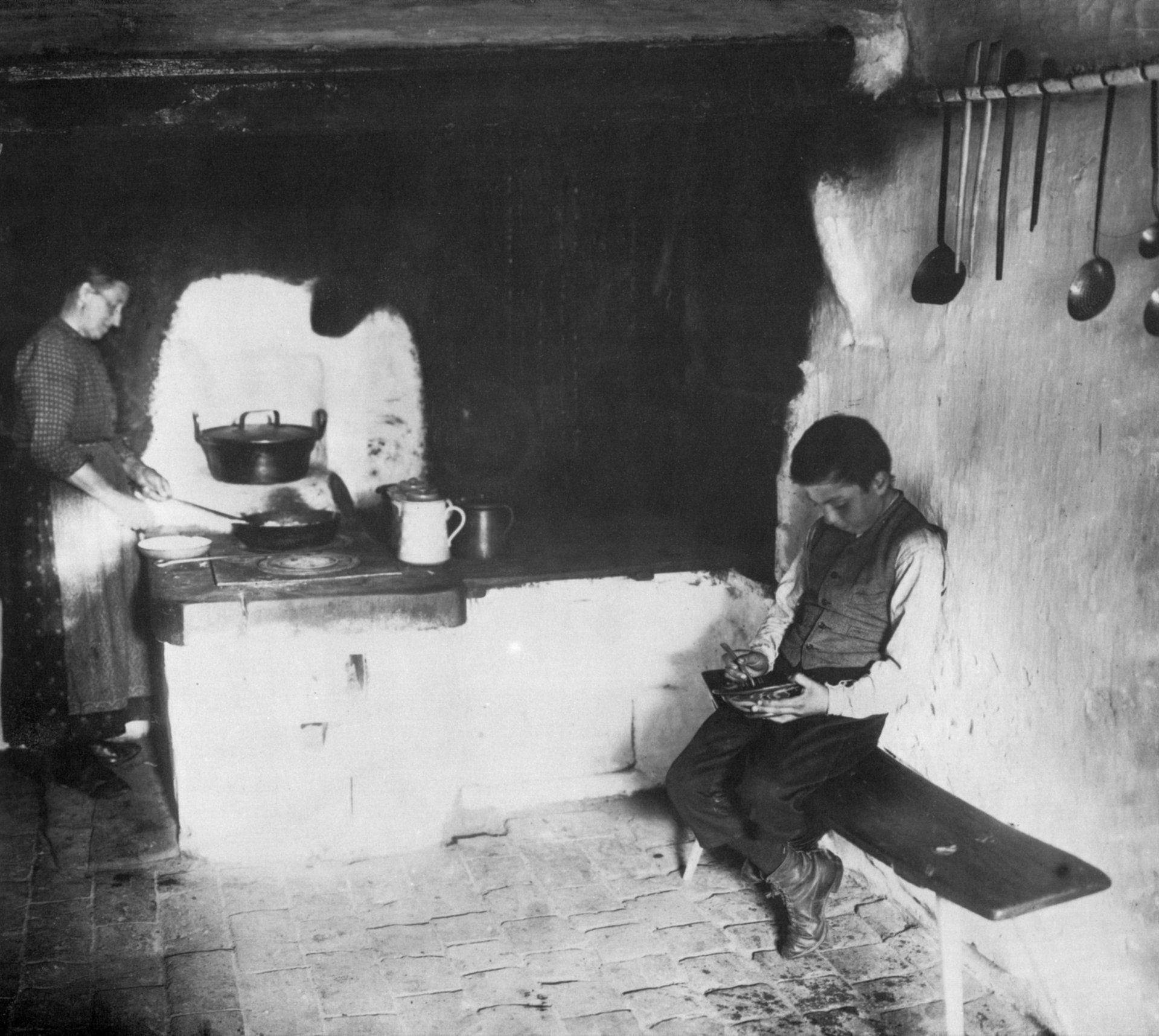 Frau kocht und junge isst auf einer Bank