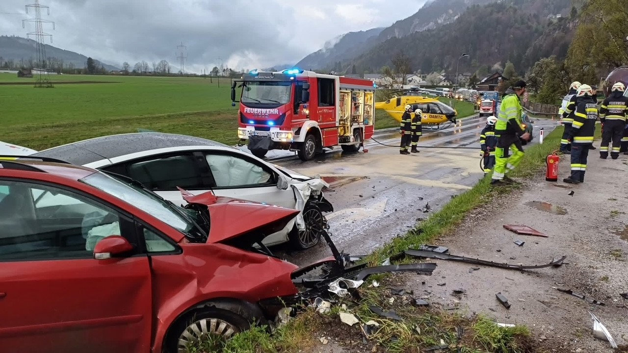 Unfallstelle mit zwei verunfallten Autos, einem Feuerwehrauto, Helikopter und mehreren Feuerwehrleuten