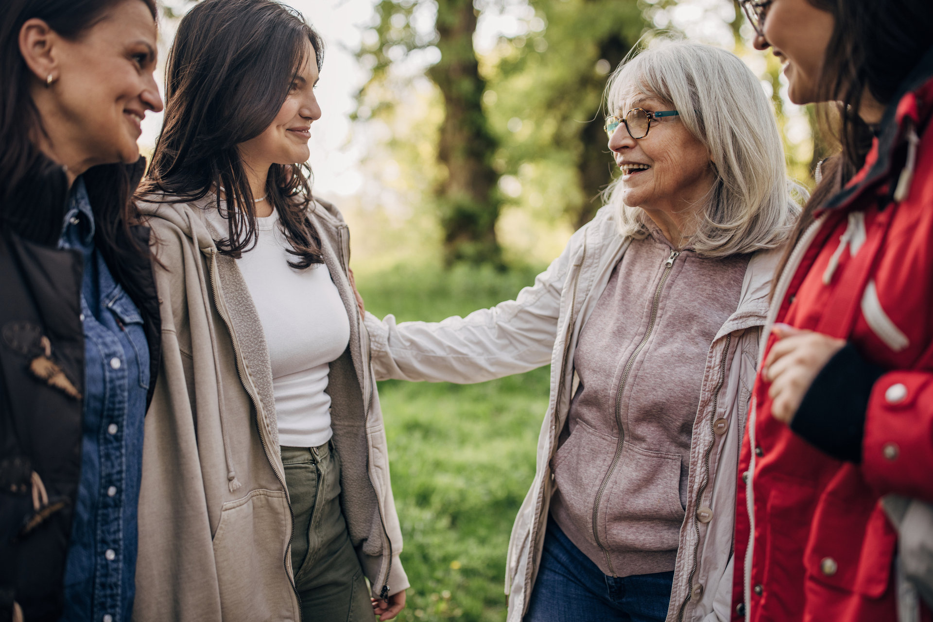 eine ältere Frau spricht mit drei mit drei jungen Frauen im Wald