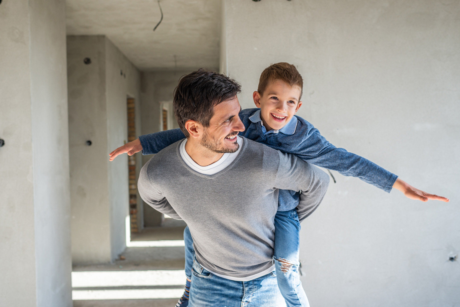 Vater in einem Rohnau hält kleines Kind Huckepack