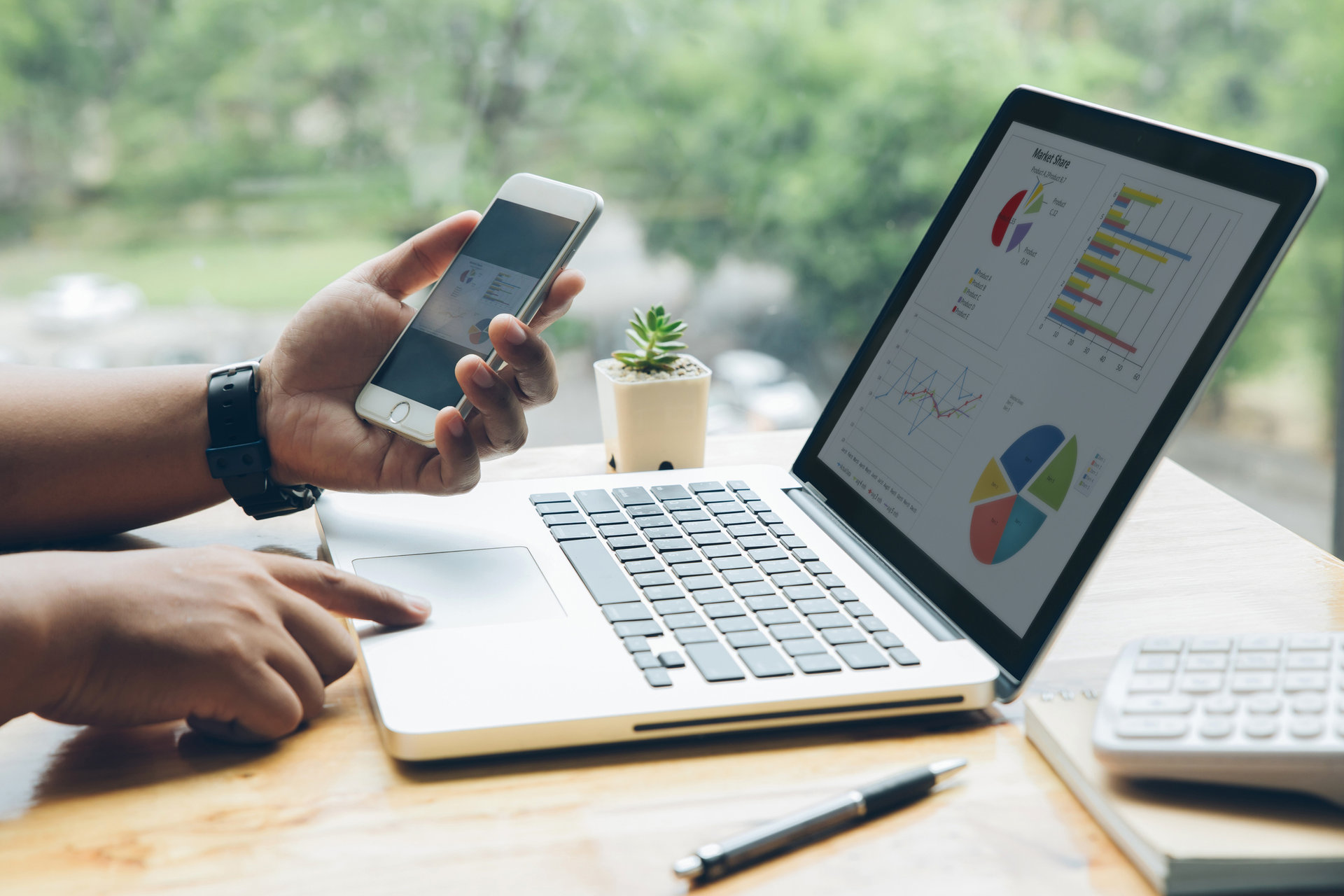 Man is working with a smart phone and laptop in his office. The concept of men working with technology.