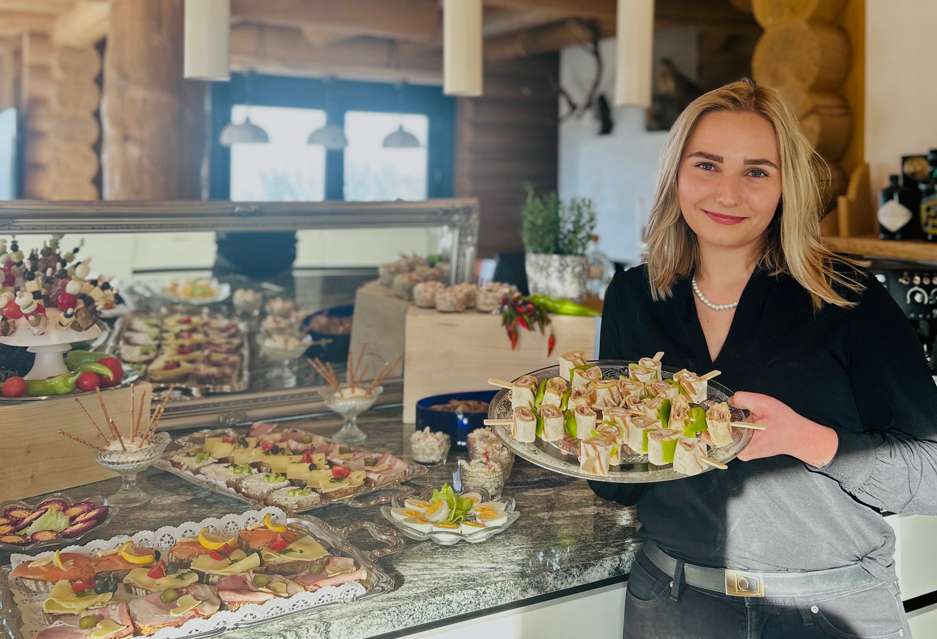 Christine Ringseis hält ein Tablett mit Essen in ihren Händen und lächelt freundlich in die Kamera.