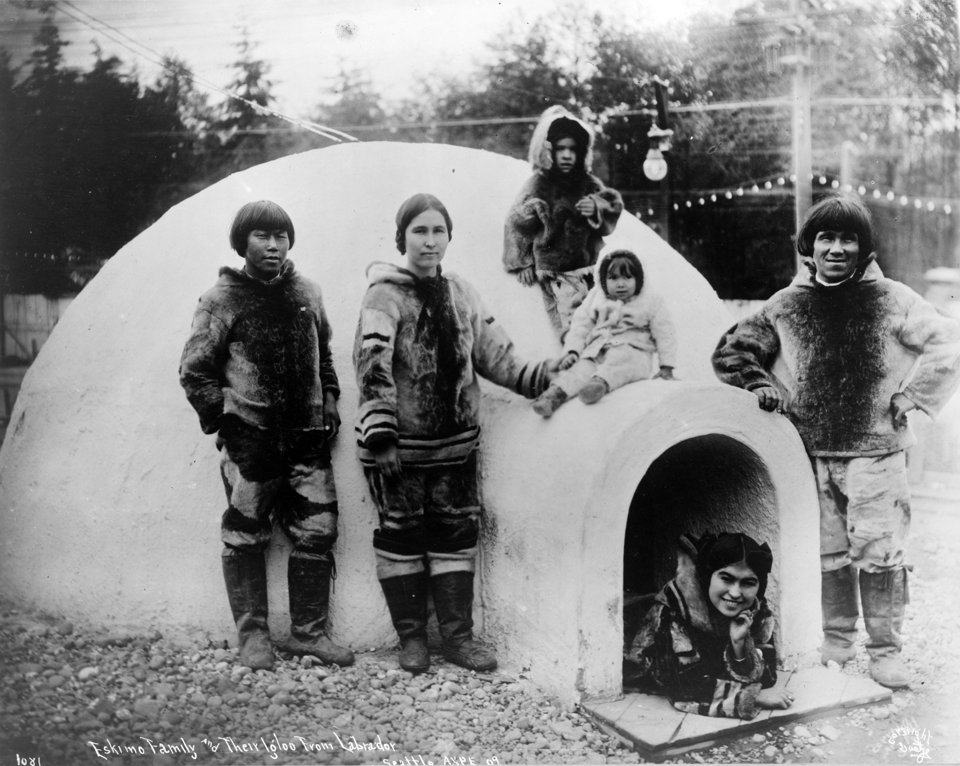Inuitfamilie mit mehreren Kindern neben ihrem Eigenheim.