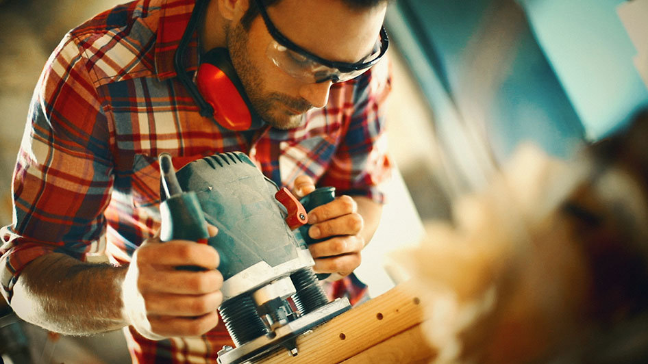 Mann arbeitet an der Maschine mit Holz © iStock | gilaxi
