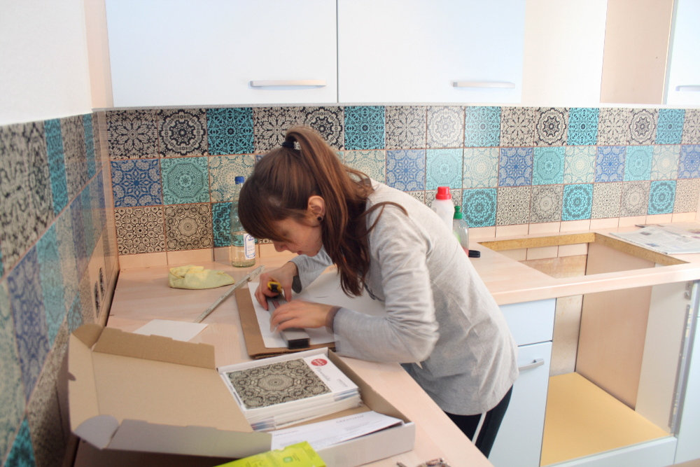 Gerade Kante: Wenn du die Folie oben ansetzt, kannst du sie unten erstmal überlappen lassen und im zweiten Arbeitsschritt an der Abschlusskante der Arbeitsplatte mit dem Scheidemesser entlangschneiden.