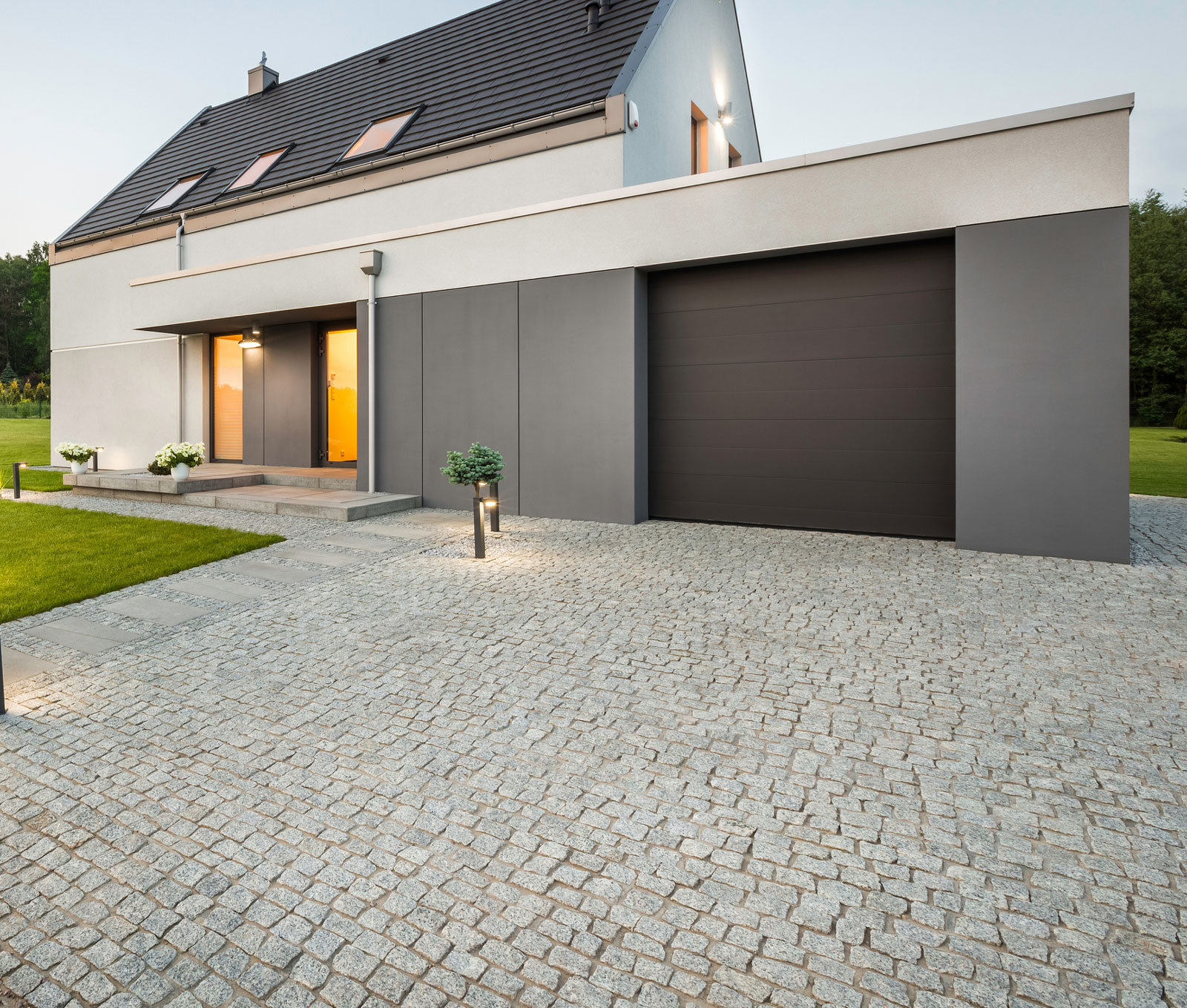 542300062 Kontrast: Sachliche Architektur und lebendiges Natursteinpflaster