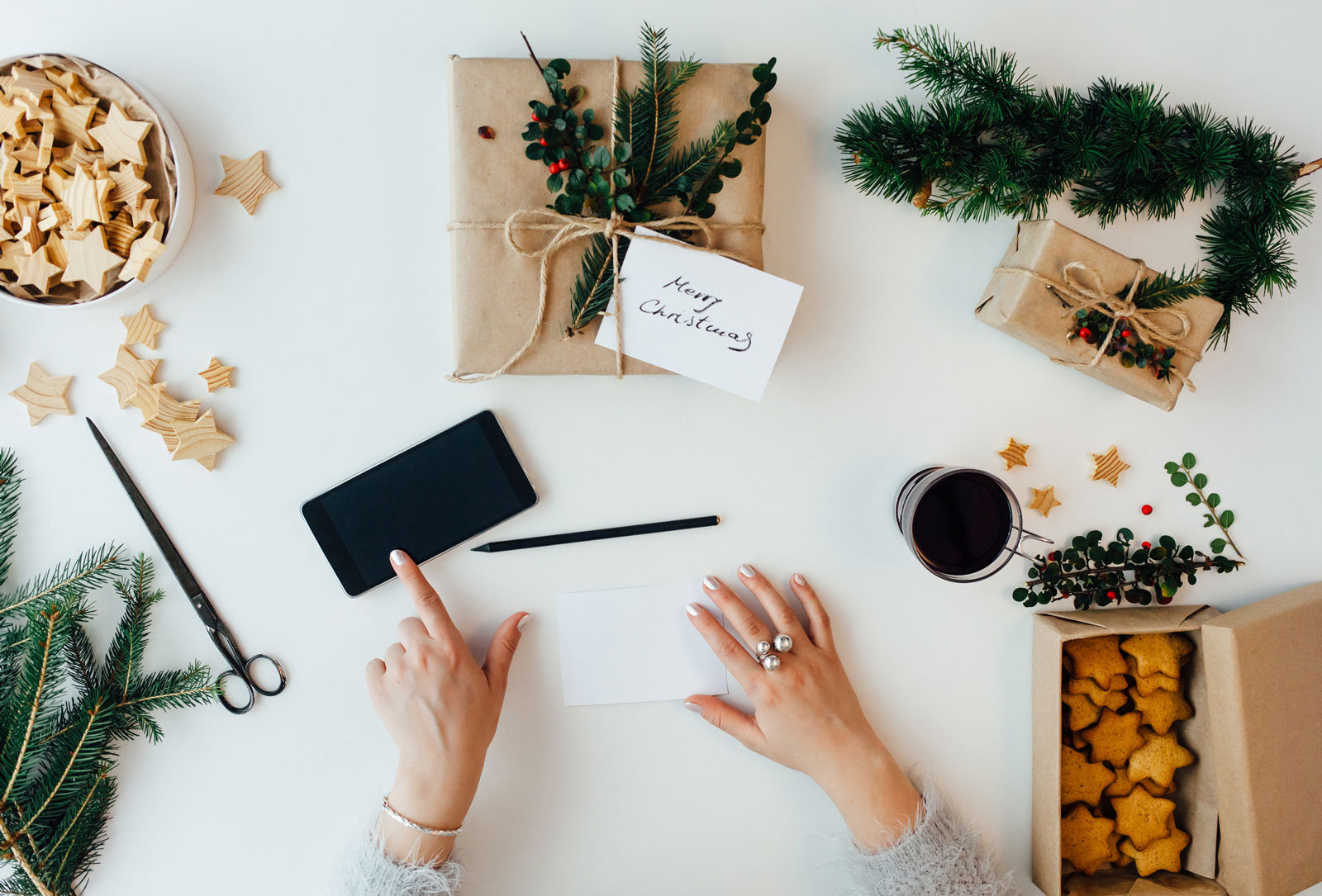 Hände mit weihnachtlicher Deko und Geschenken