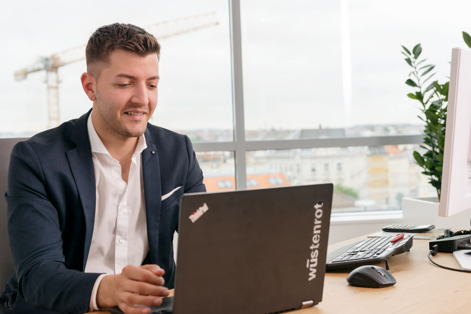Mann im Anzug an einem Laptop sitzend
