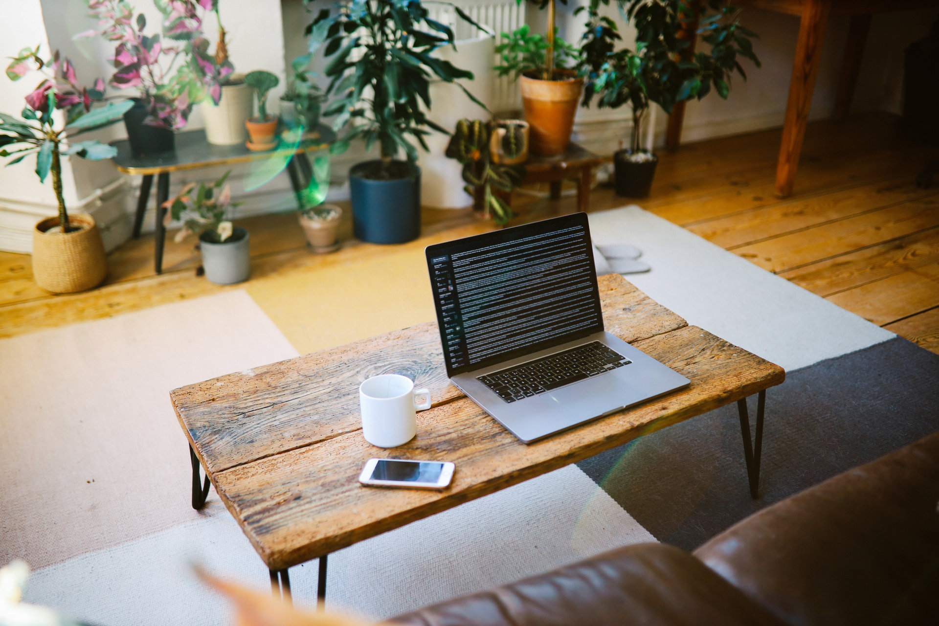 Setup for working at home, laptop at the table in the living room and a coffee cup.