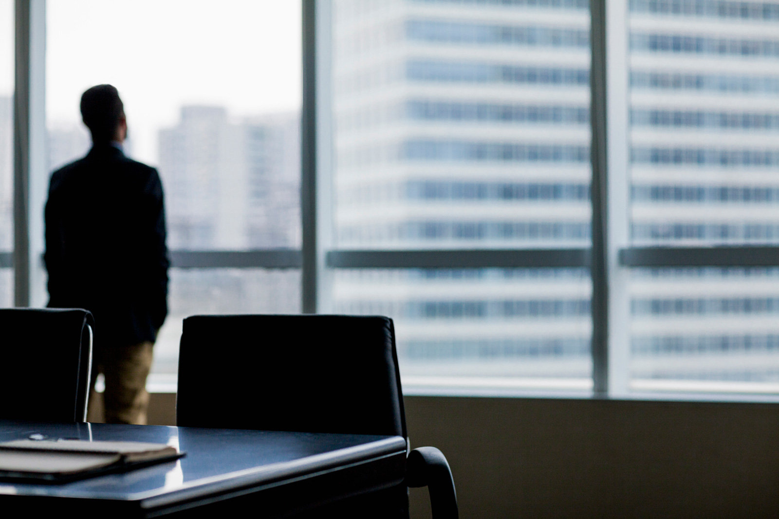 Verblastes Bild, das einen Mann in einem Büro zeigt, der gerade aus dem Fenster schaut.
