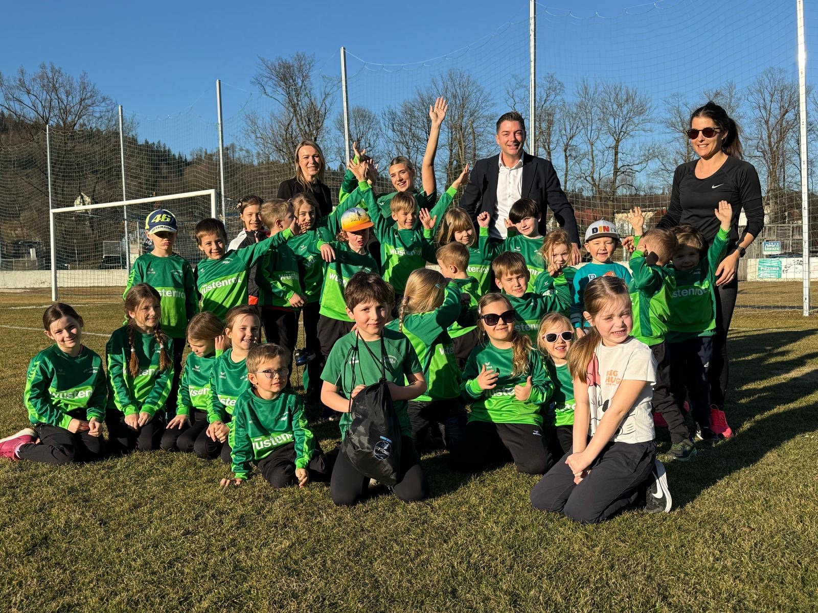 Johann Edlinger mit einem Kinder Fußball Verein auf einem Fußballplatz.
