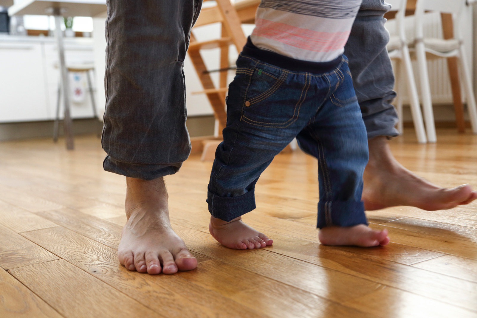 Die Füße eines Erwachsenen zusammen mit den Füßen eines Kleinkinds