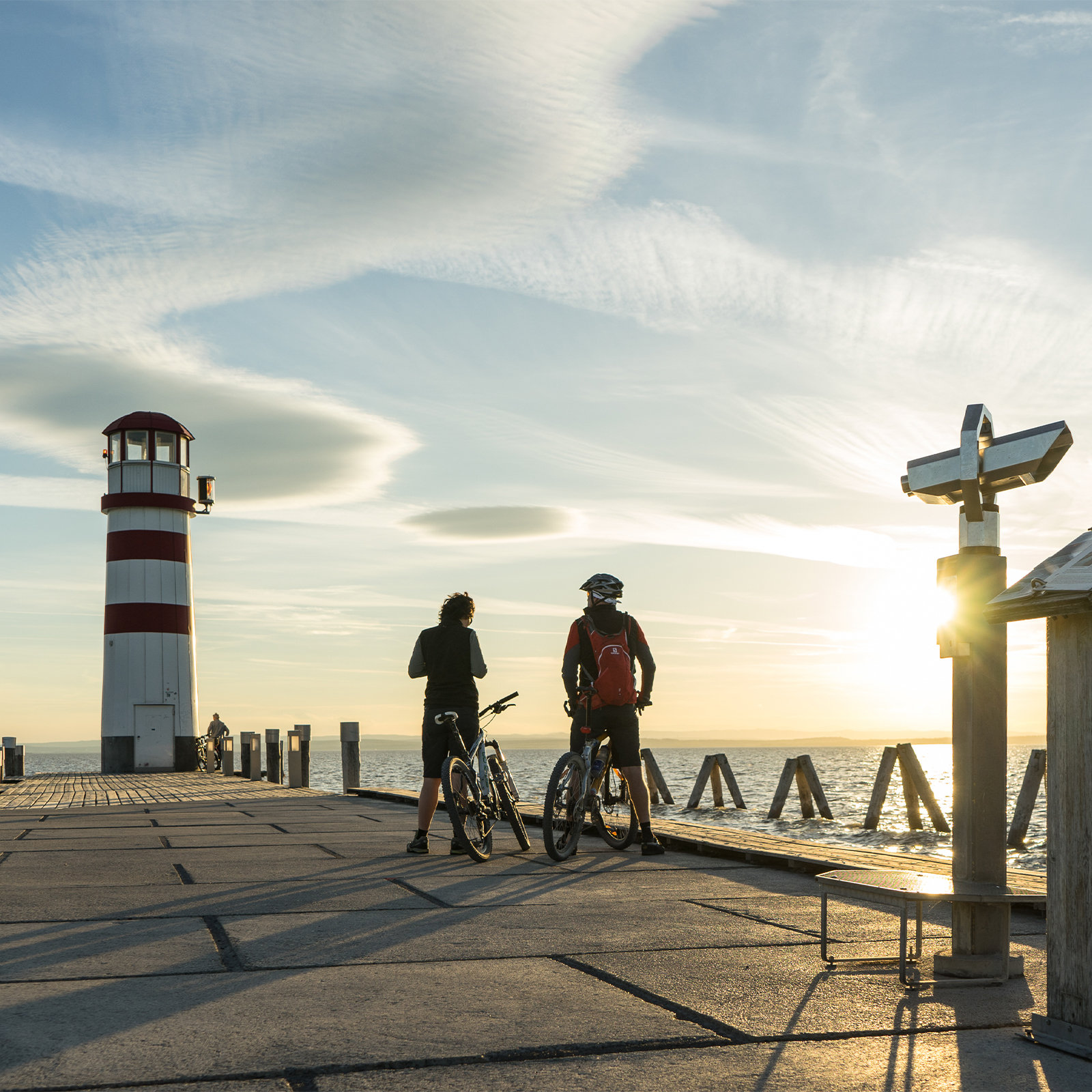 Zwei personen schauen sich den Sonnenuntergang am Meer an, auf ihren Fahrrädern