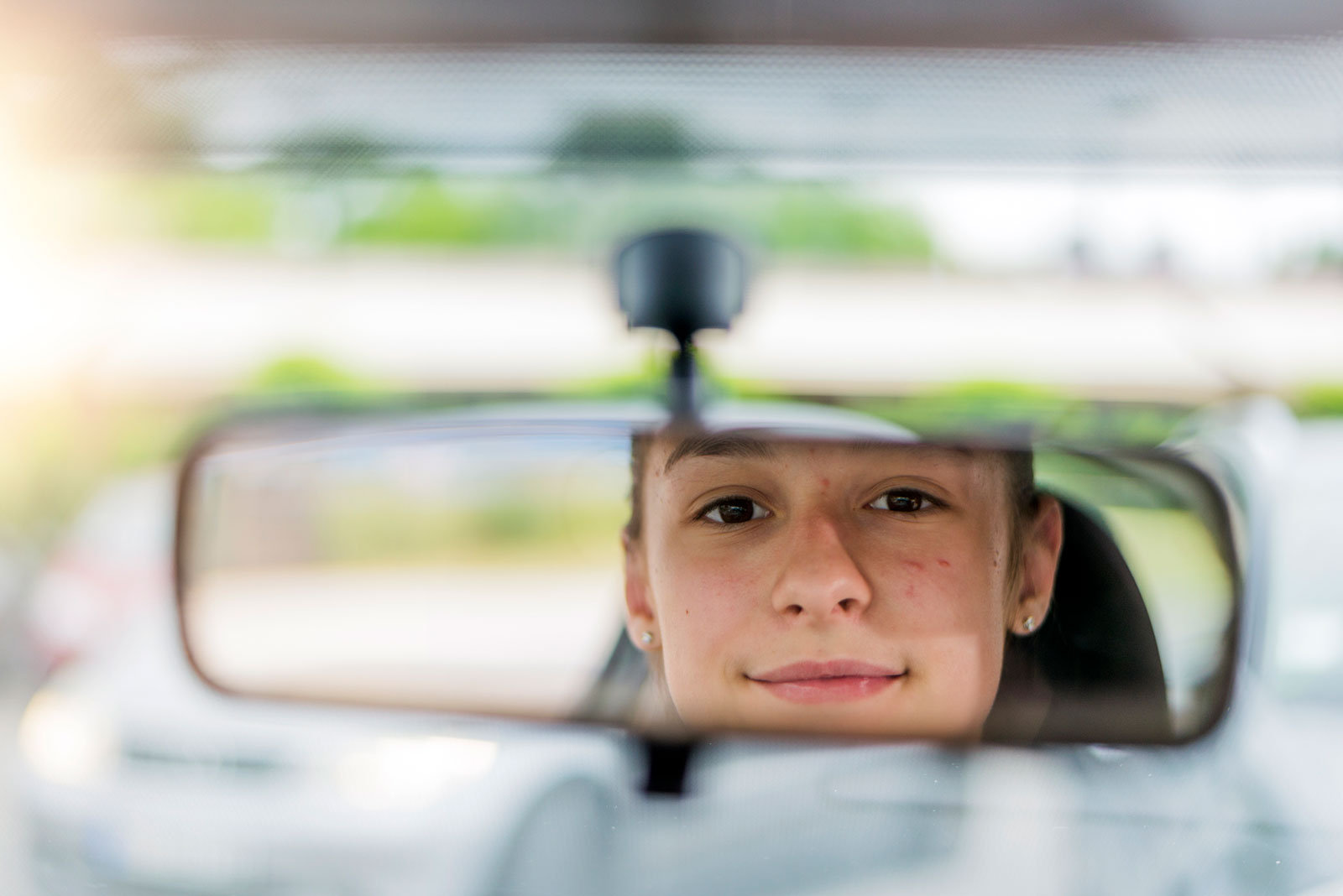 Gesicht einer jungen Person, die in den Fahrerspiegel schaut