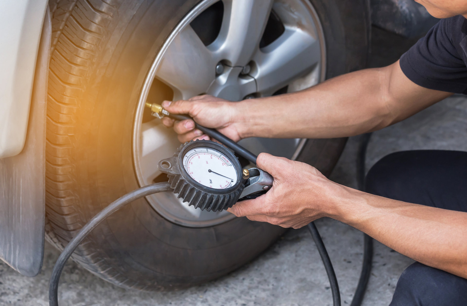 Close up mechanic inflating tire and checking air pressure with gauge pressure in service station