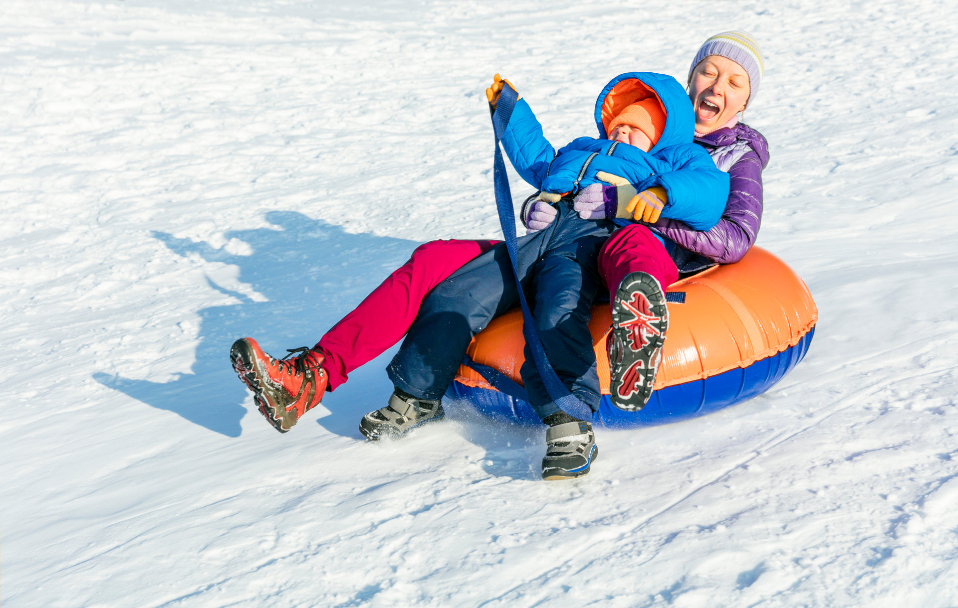 Mutter rodelt mit Kind auf einem Snowtube-Schlauch