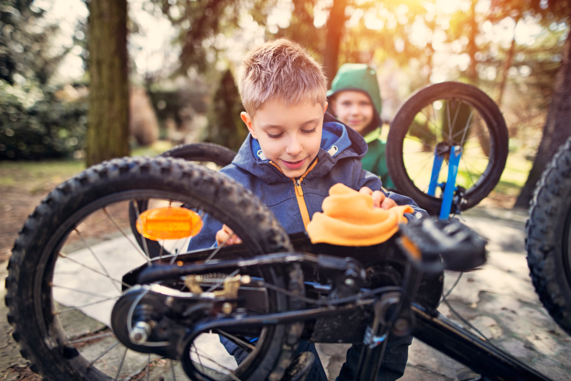 Little boys tending to their bicycles after winter. Little brothers aged 7 cleaning and repairing their bicycles after winter.