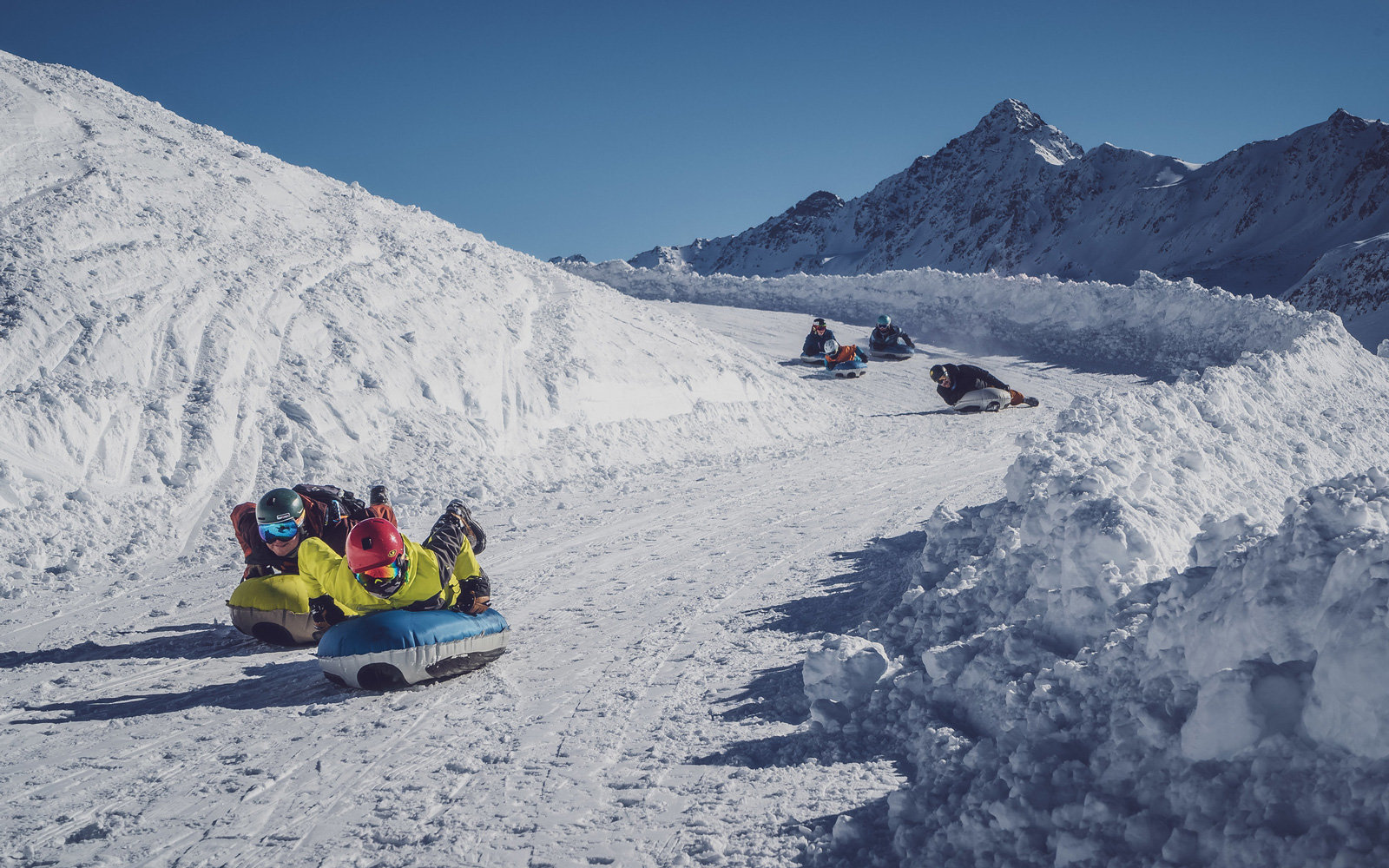 Personen auf Luftkissen auf einer Skipiste
