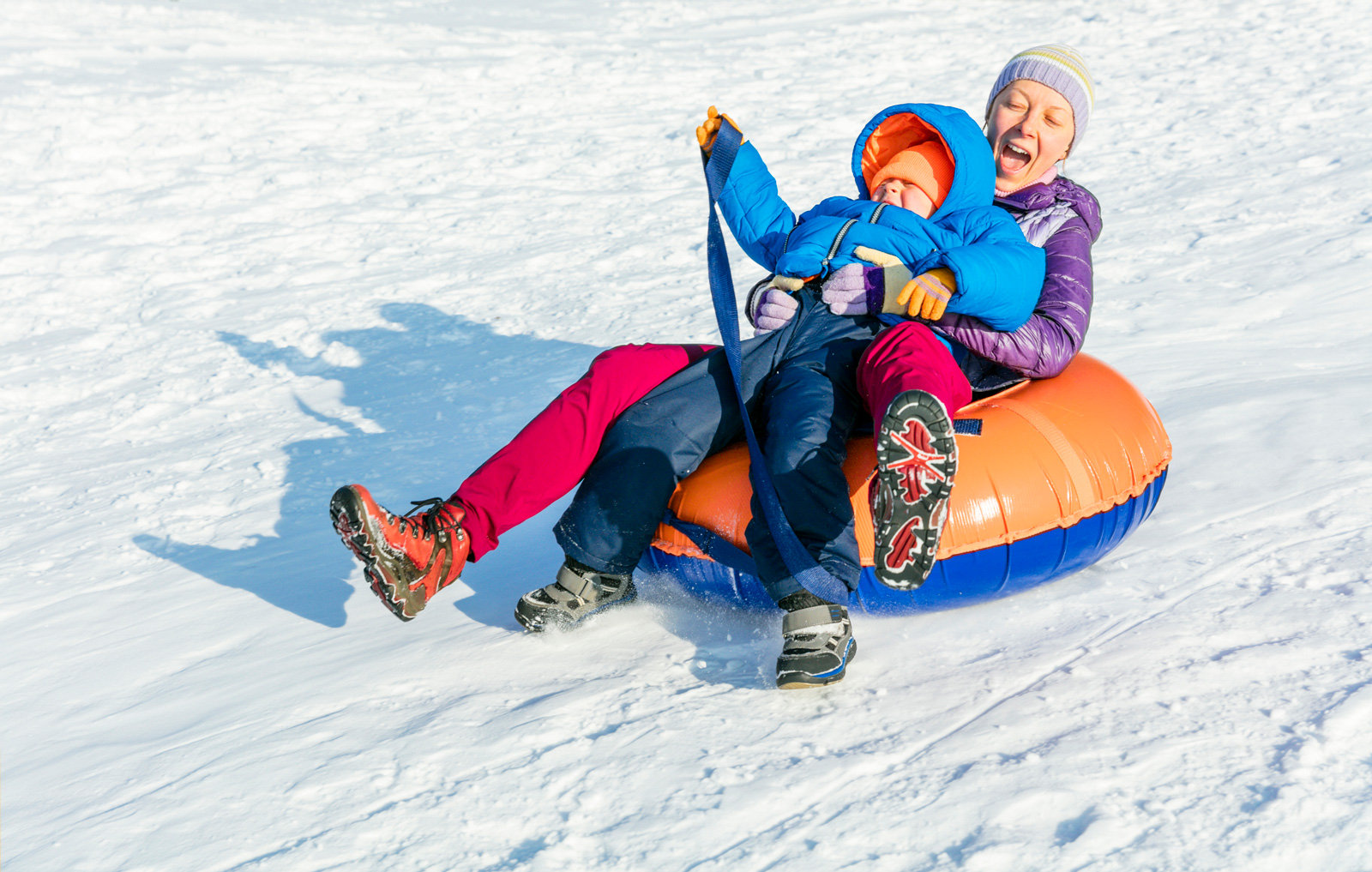 Erwachsene mit Kind auf Luftkissen auf Skipiste