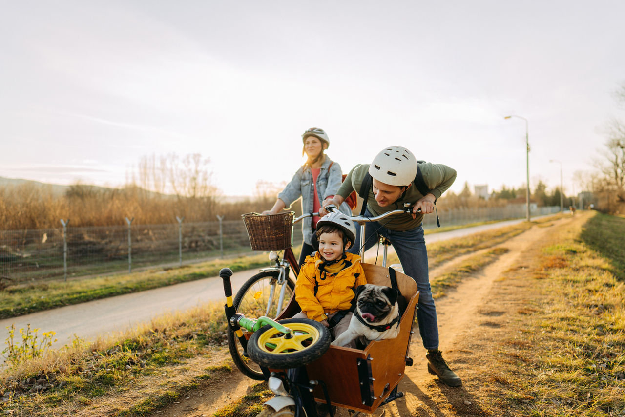 Radausflug mit Lastenfahrrad Familie mit Fahrrad und Lastenfahrrad, Kind sitzt mit Hund und Roller vorne