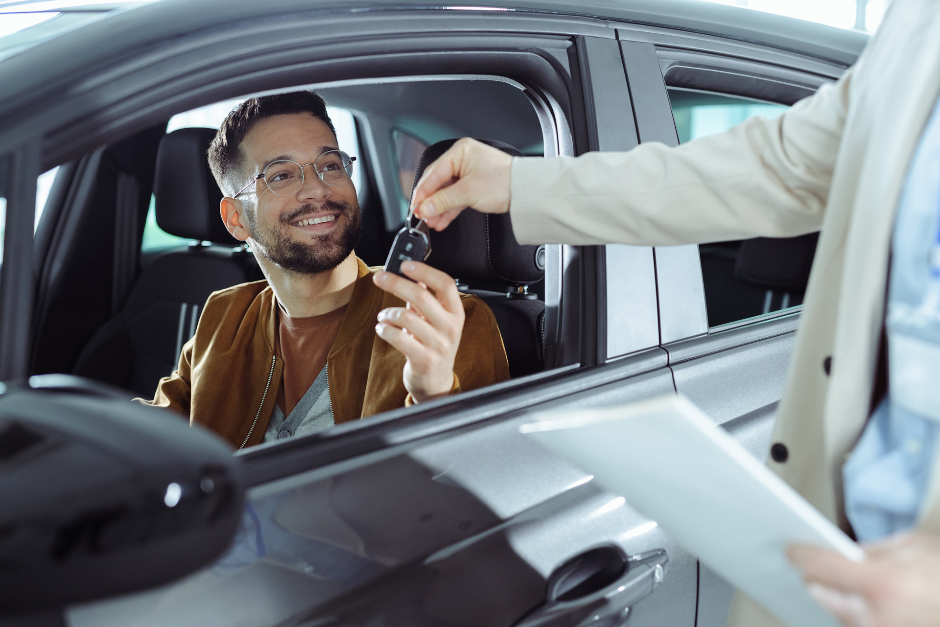 Time to say good bye Happy man receiving keys for his new car in a showroom