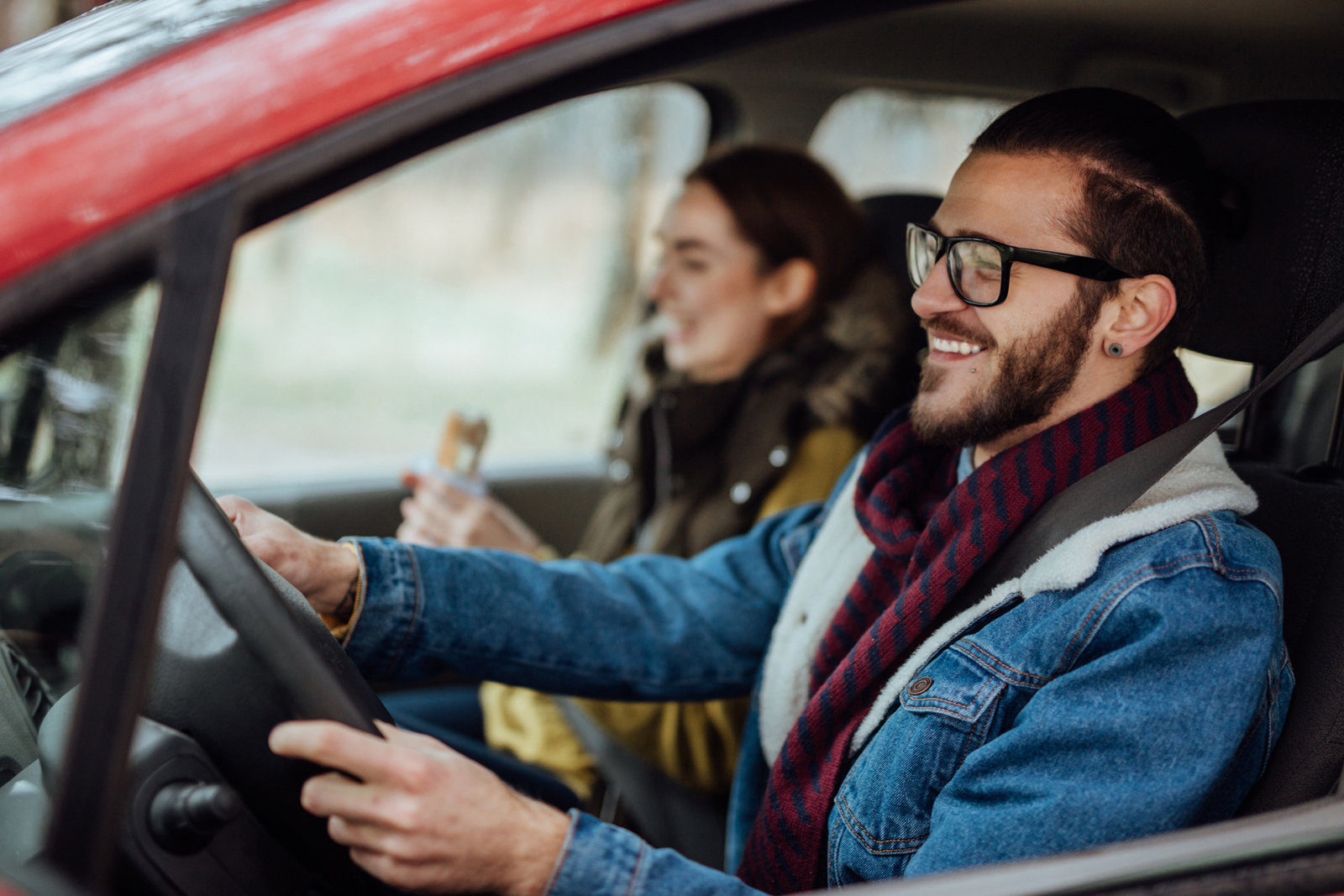 Päärchen sitzt im Auto und lacht beim Fahren.