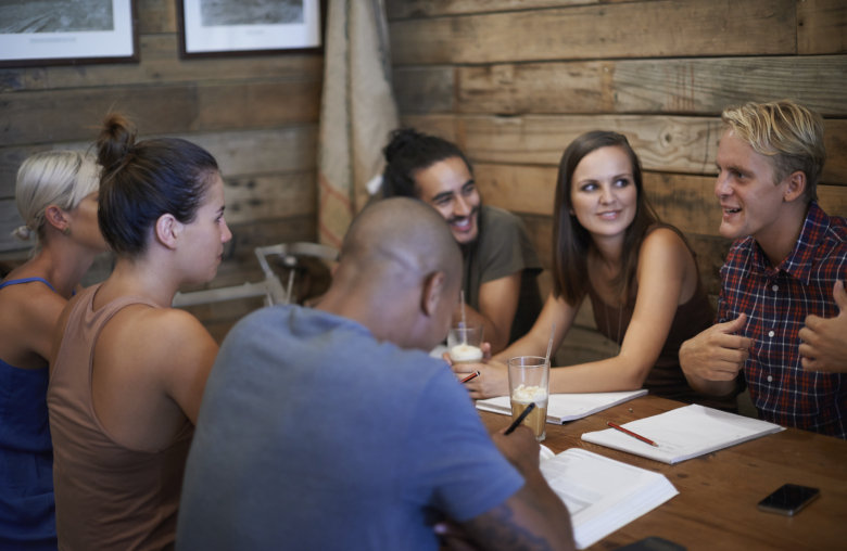Gruppe von Jugendlichen sitzt in einer Holzhütte.