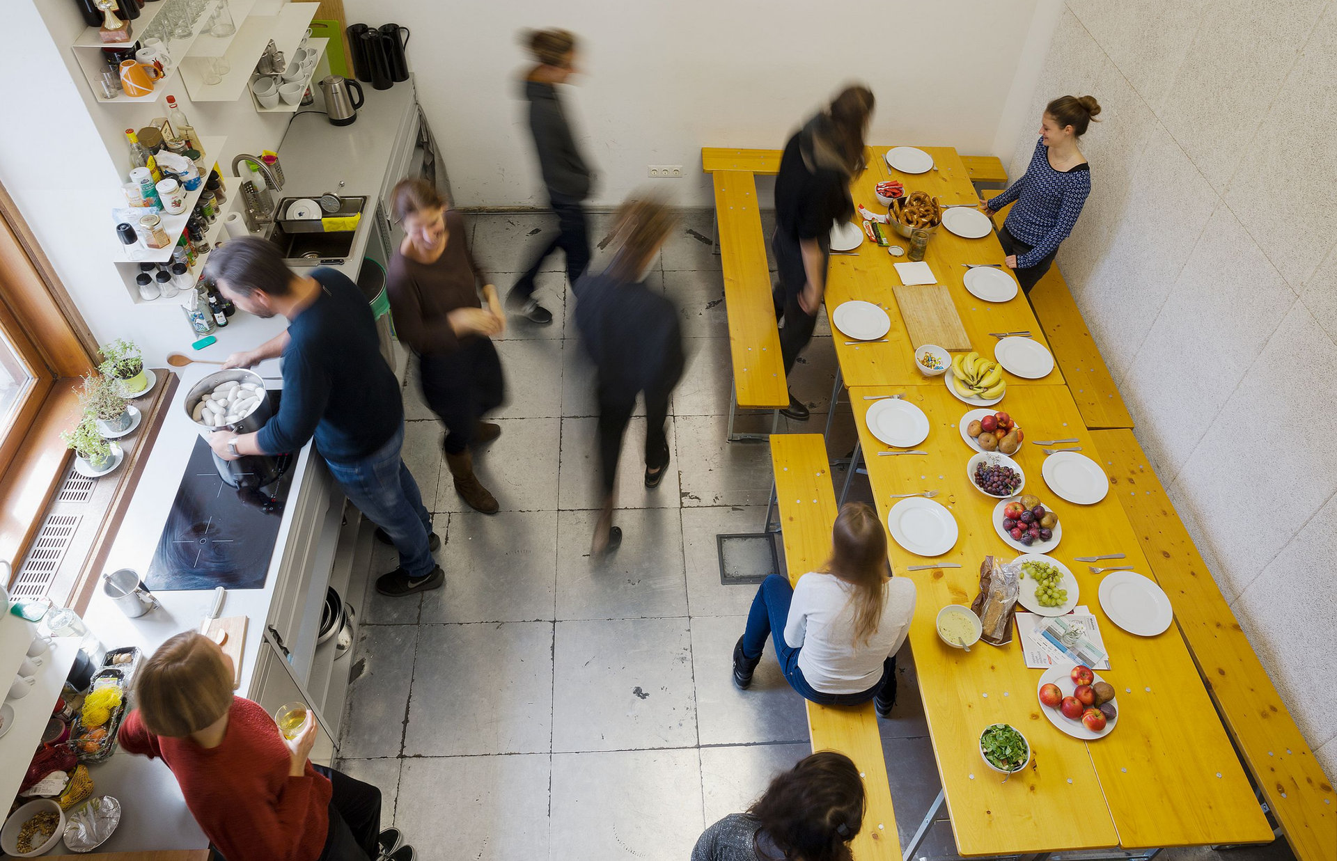 Mitarbeiter und Mitarbeiterinnen kochen und essen zusammen