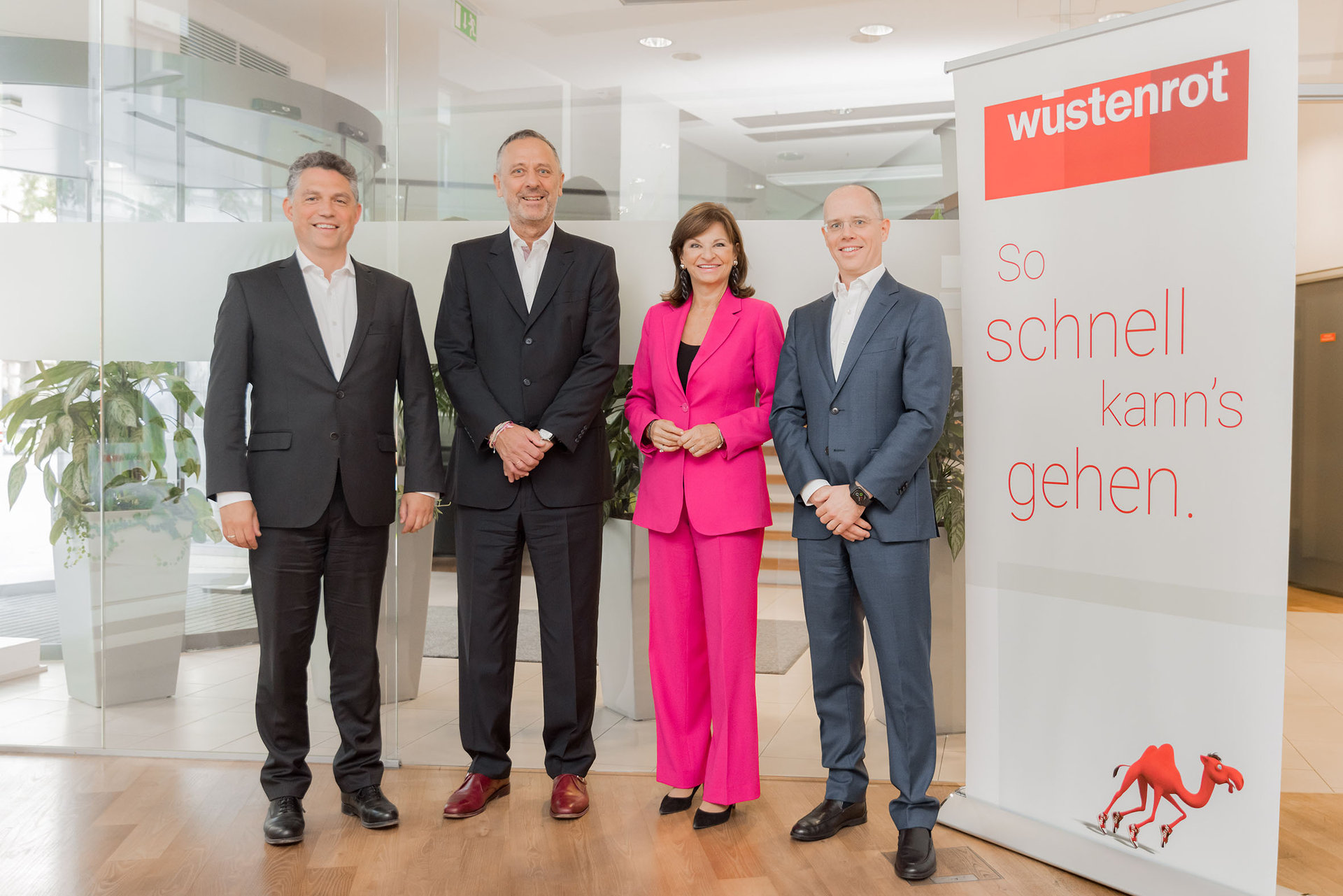 Vorstandsmitglieder Gregor Hofstätter-Pobst, Wolfgang Hanzl, Susanne Riess-Hahn und Peter Steinbauer stehen vor einem Wüstenrot Werbeplakat mit dem Slogan: Wüstenrot - so schnell kann's gehen.