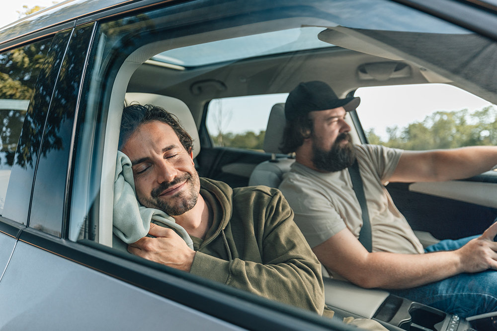 Zwei Personen sitzen entspannt in einem Auto. 