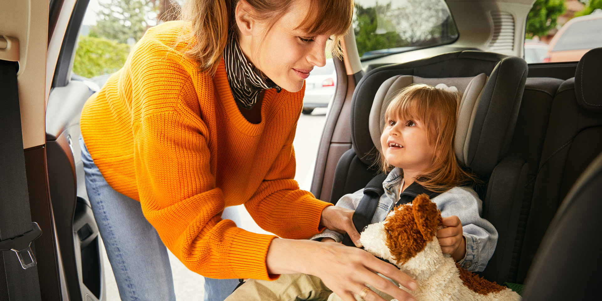 Eine Frau schnallt ihr Kind auf dem Rücksitz an, da ihr Sicherheit sehr wichtig ist. 