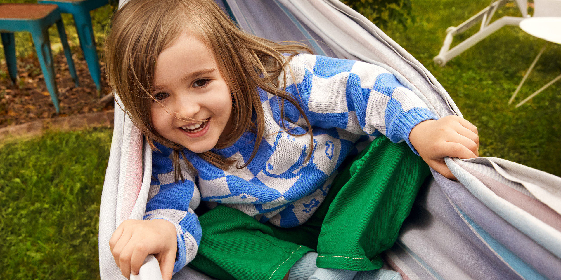 Mädchen sitzt in einer Hängematte und hat ein glückliches Gesicht.