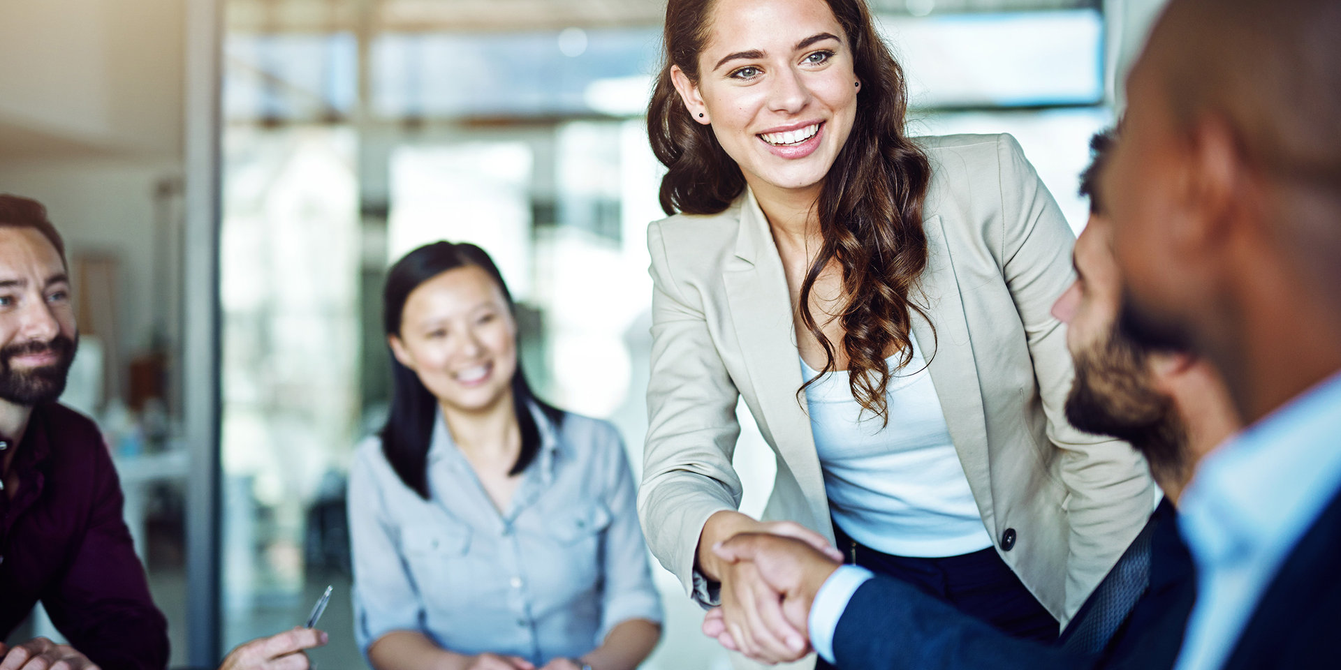 In einem Geschäftsmeeting stellen sich Personen lachend einander vor.