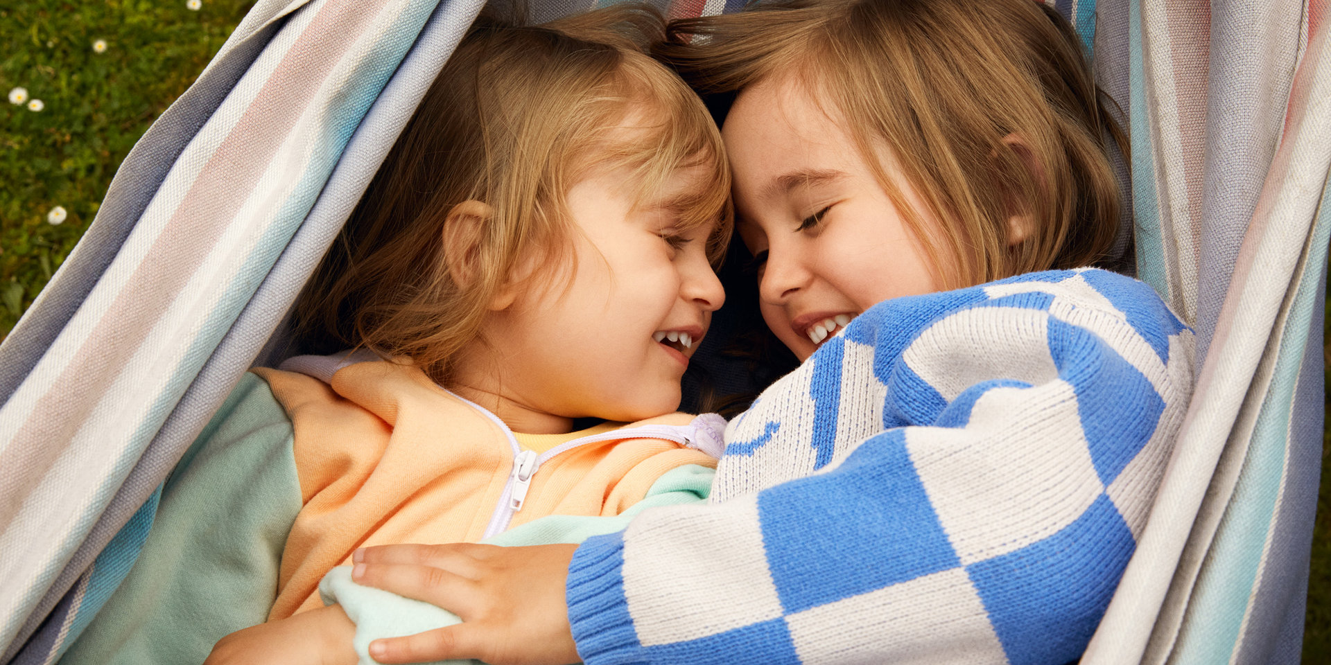 Zwei Kinder liegen in Hängematte und lachen
