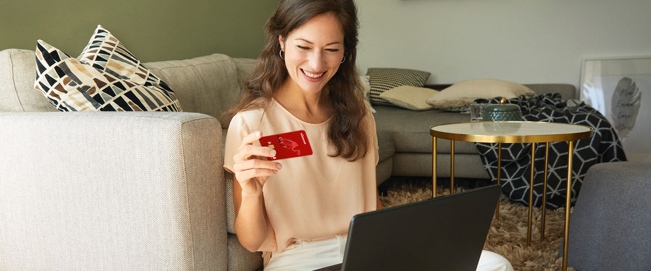 Frau sitzt mit Bankkarte vor Laptop
