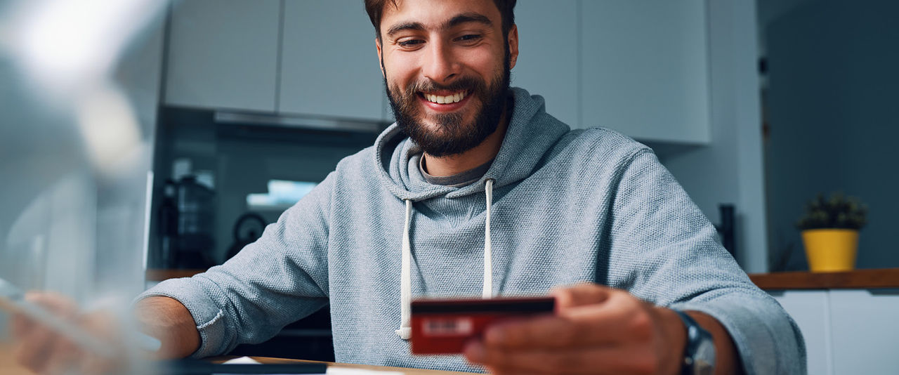 Mann wirft einen lächelnden Blick auf seine Bankkarte